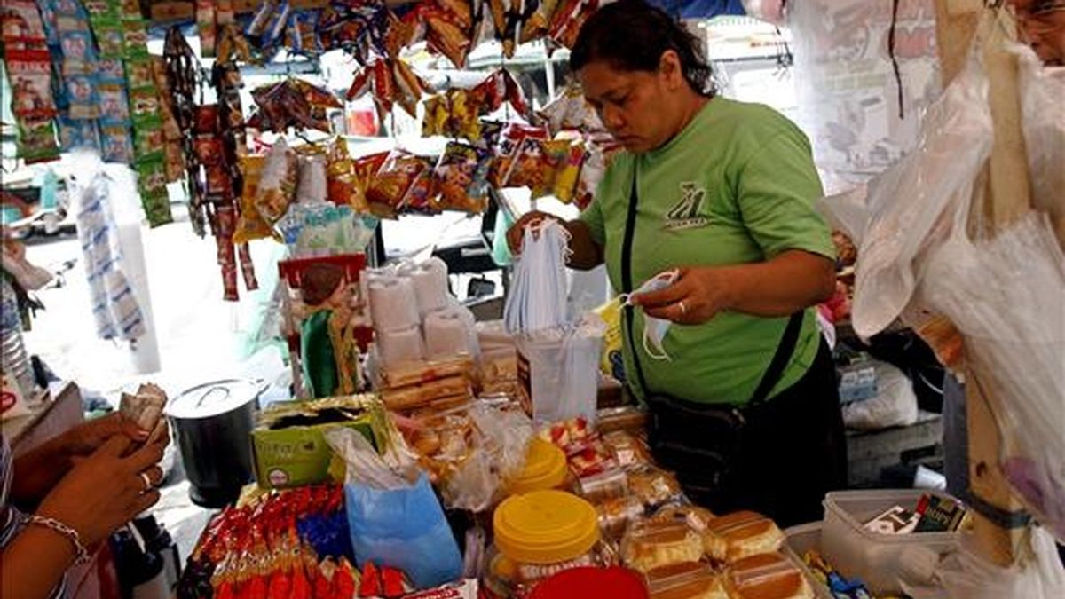 Una vendedora atiende a una clienta en un puesto callejero de Manila (Filipinas), hoy, 12 de junio. La Organización Mundial de la Salud (OMS) ha informado de la existencia de casi 30.000 casos de gripe A, con 145 muertos en 74 países. EFE