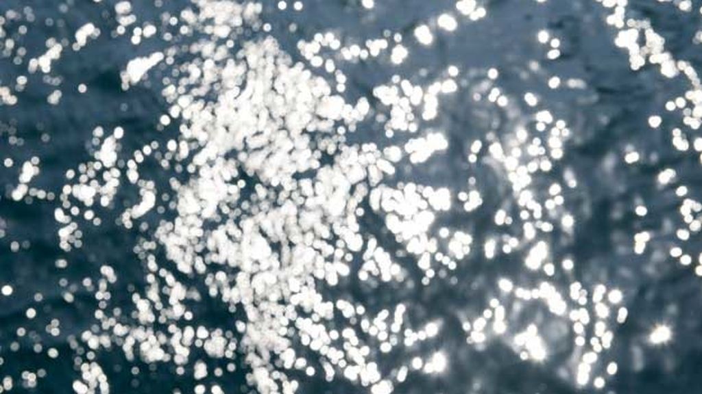 Sol al amanecer, brillo en las olas: el tintineo en las olas que se extiende hasta el horizonte