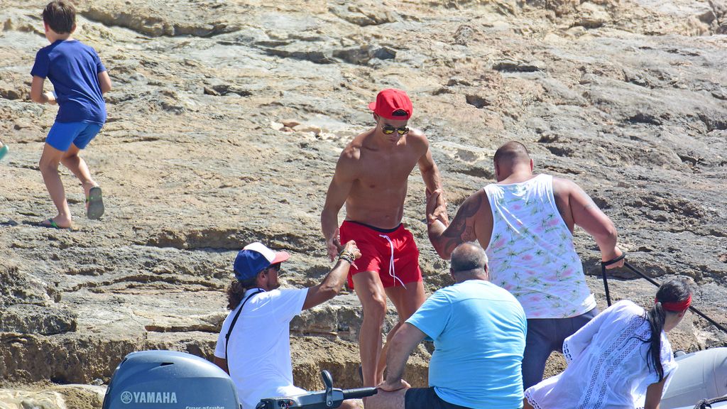 Cristiano, con su inseparable gorra roja, sube a la embarcación