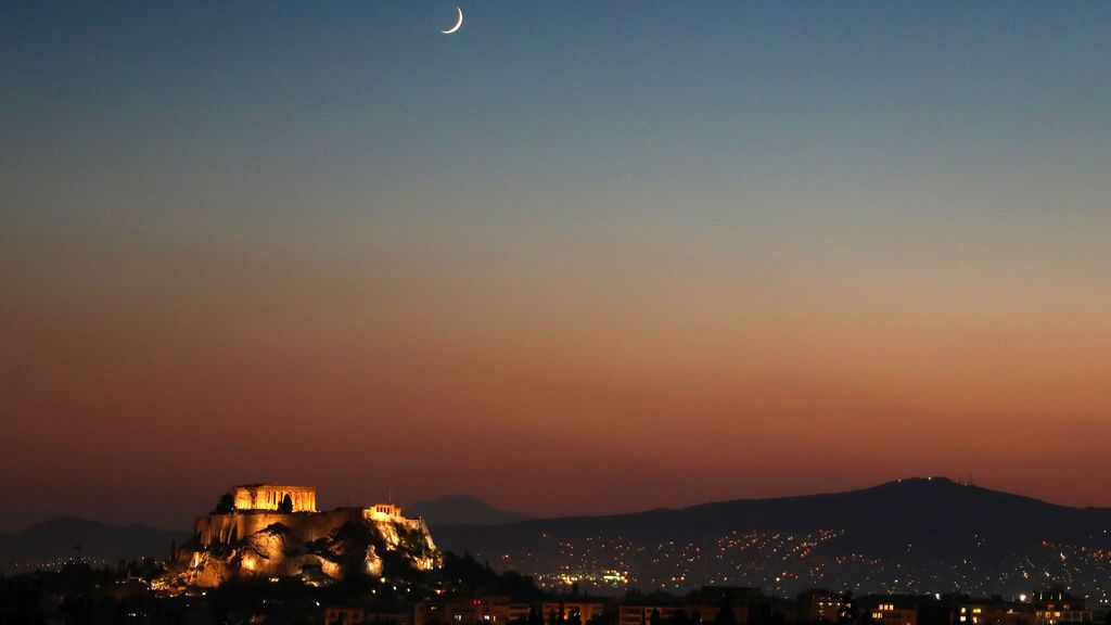 Luna creciente detrás del templo iluminado del Partenón en Atenas