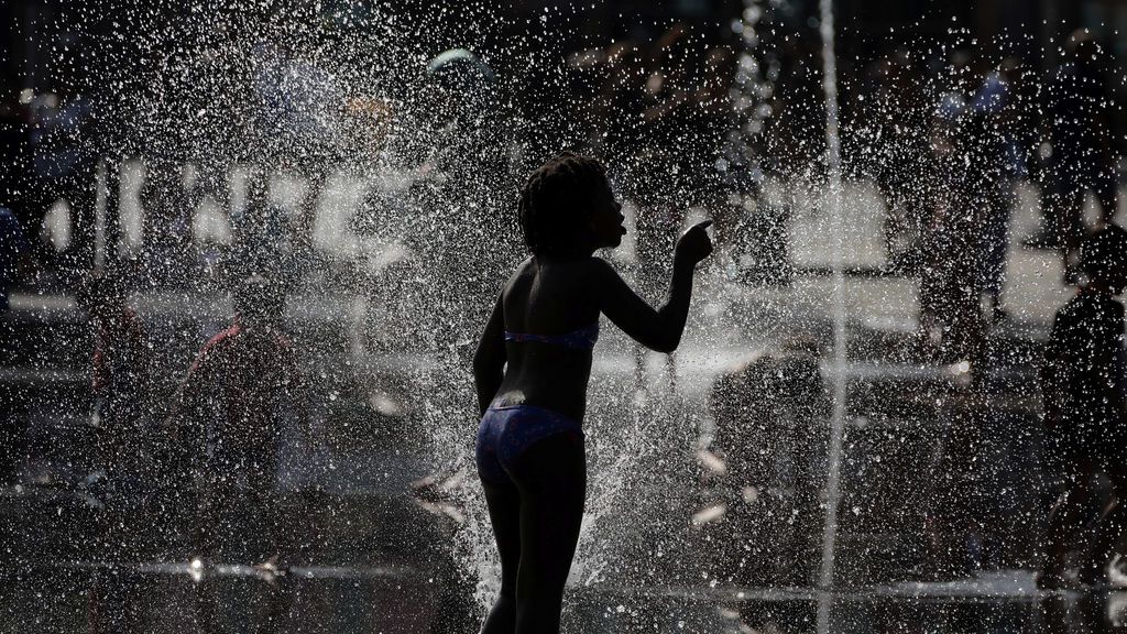Niña se refresca en una fuente en Niza, Francia