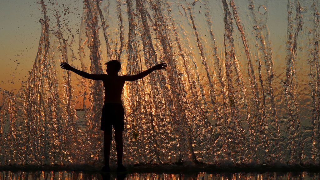Un niño disfruta del agua durante la puesta de sol en el puerto de Sebastopol, Crimea