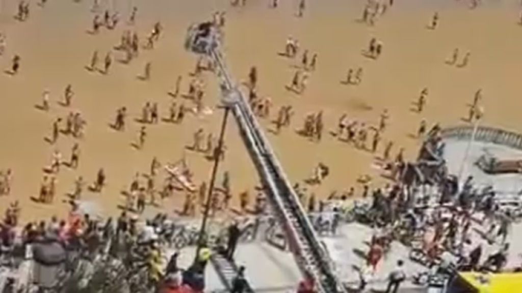 Los bomberos rescatan con una grúa a una mujer de la playa de La Concha