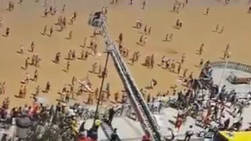 Los bomberos rescatan con una grúa a una mujer de la playa de La Concha