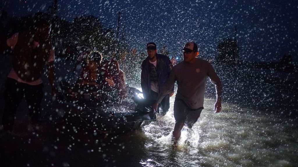 Voluntarios ayudan a empujar una barca con evacuados durante la tormenta tropical Harvey