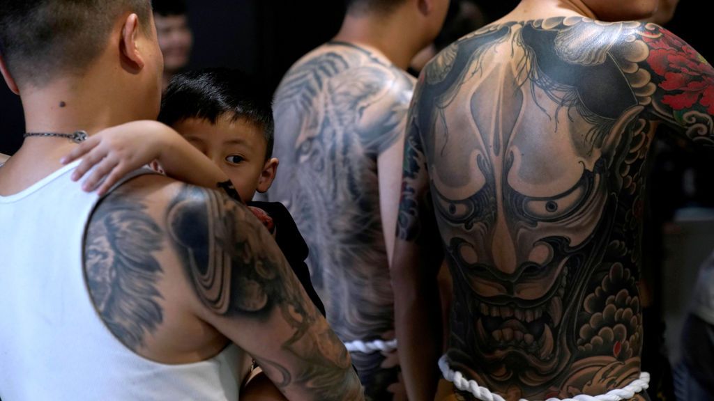 Un padre coge a su hijo en la exposición de tatuajes extremos y arte corporal en Shangai
