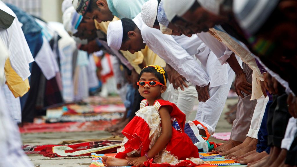 Una niña mira a los musulmanes durante sus plegarias durante el festival Fid al-Adha