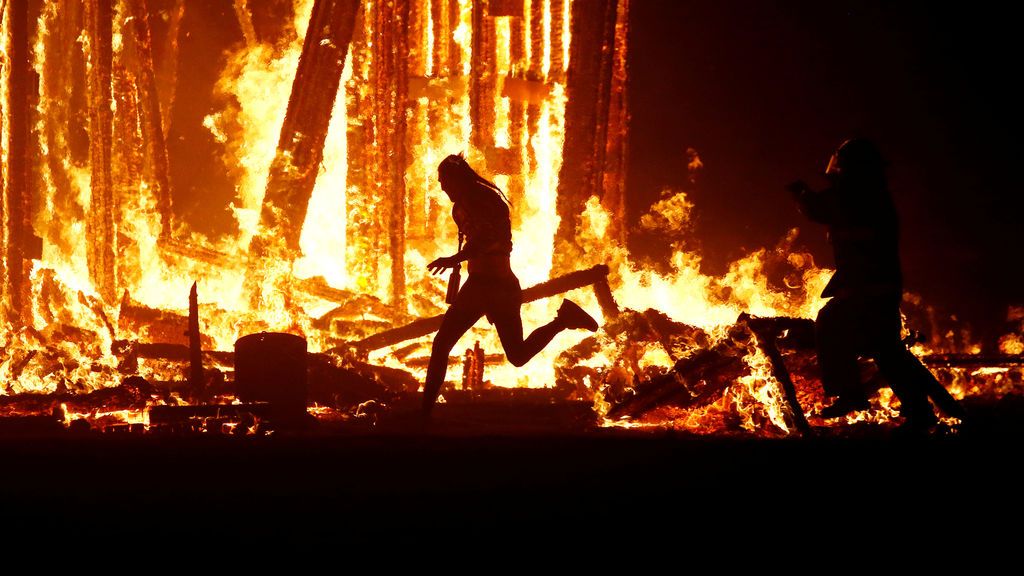Un participante del festival ‘Burning Man’ corre hacia el centro de las flamas