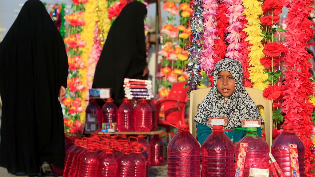 Una chica vende agua y flores en el cementerio ‘Valle de la Paz’ durante el festival musulmán de Eid al-Adha en Najaf