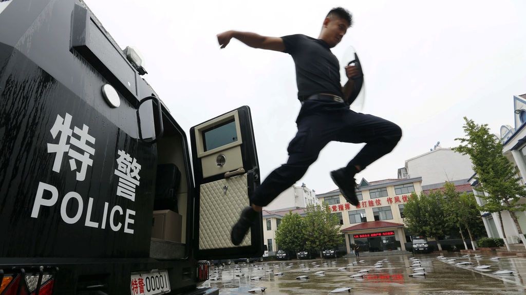 Un policía salta fuera de la furgoneta durante una sesión de entrenamiento en China