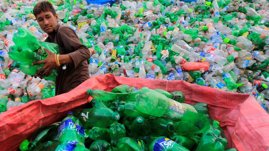 Un trabajador ordena botellas para triturarlas en una planta de reciclaje en Pakistán