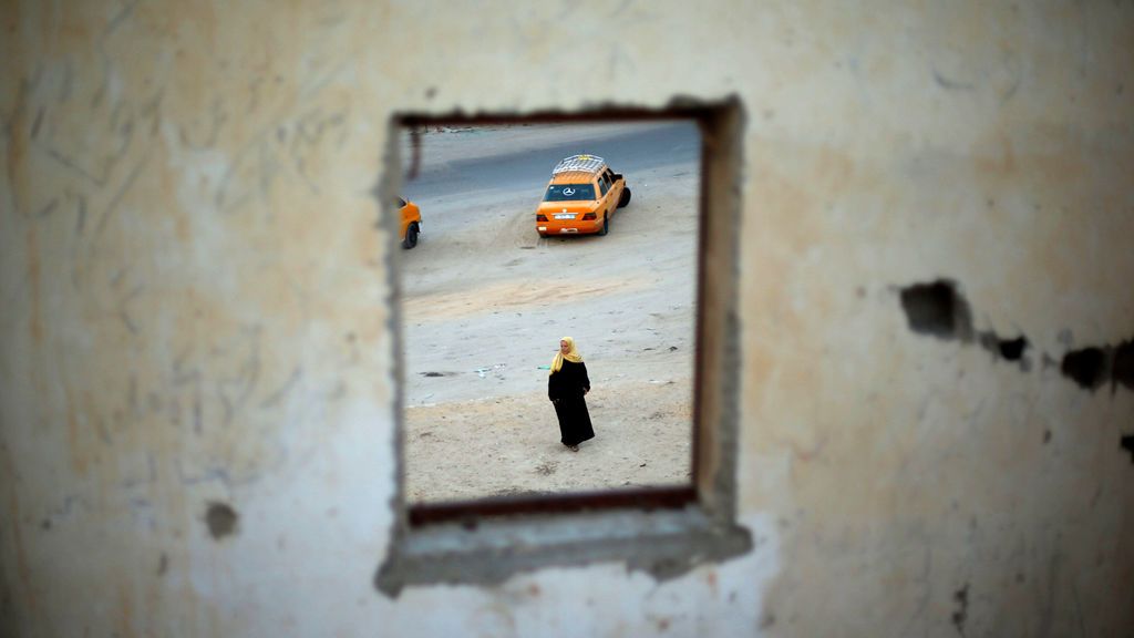 Una mujer palestina es vista a través de una ventana mientras espera el regreso de sus familiares en Gaza