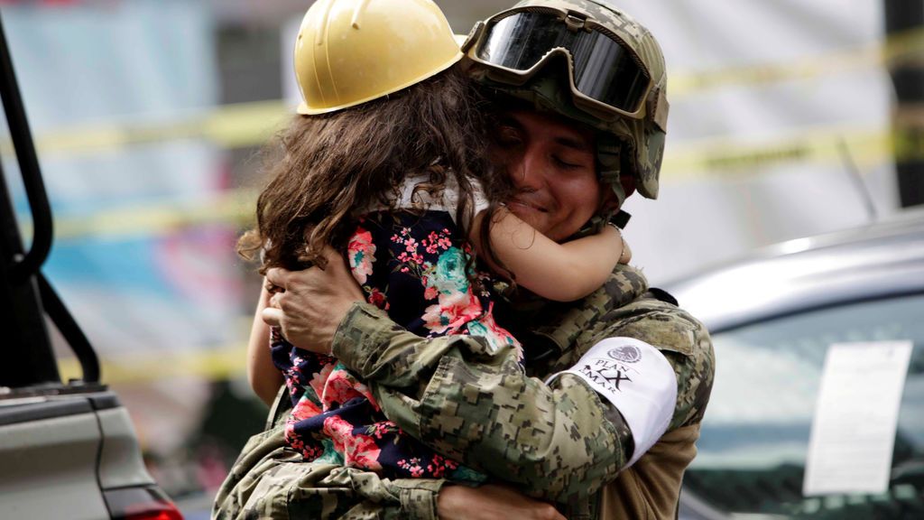 Una niña ofrece abrazos a las personas cerca de un edificio derribado durante el terremoto de México