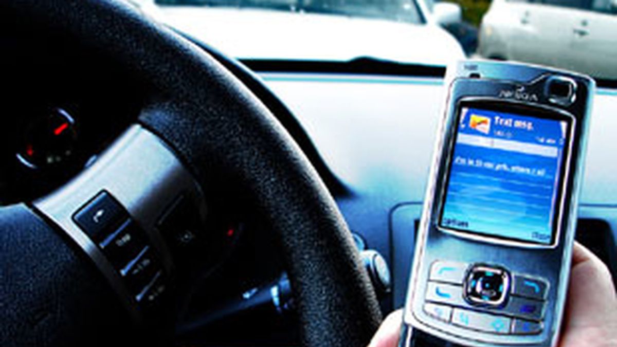 Un conductor escribe un SMS en su móvil.