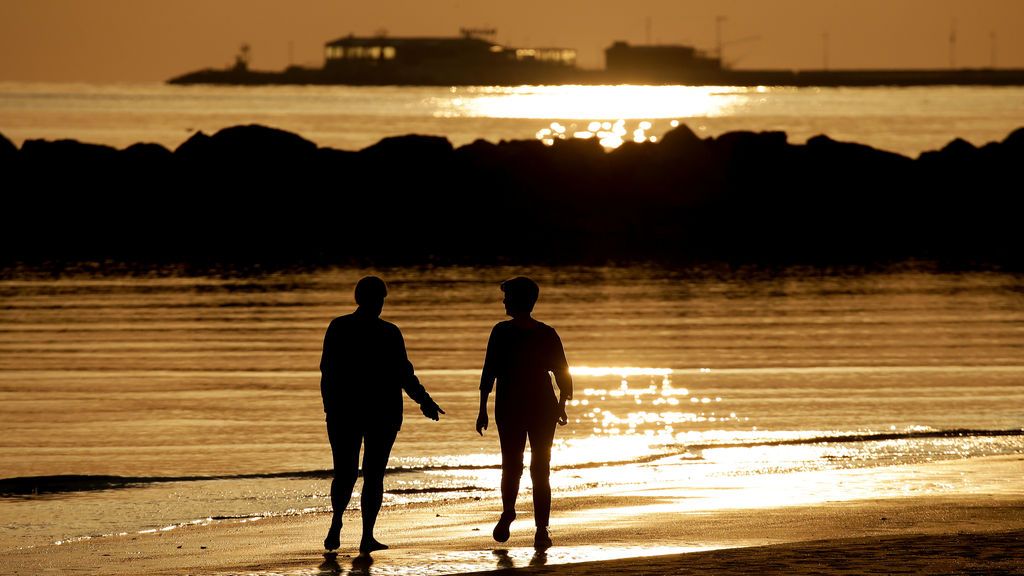 Dos mujeres caminan por la orilla al alba en la playa de Rimini, Italia