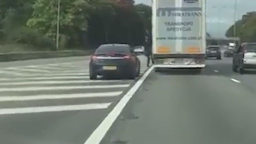 Un grupo de inmigrantes saltan de un camión en marcha y esquivan el tráfico para huir