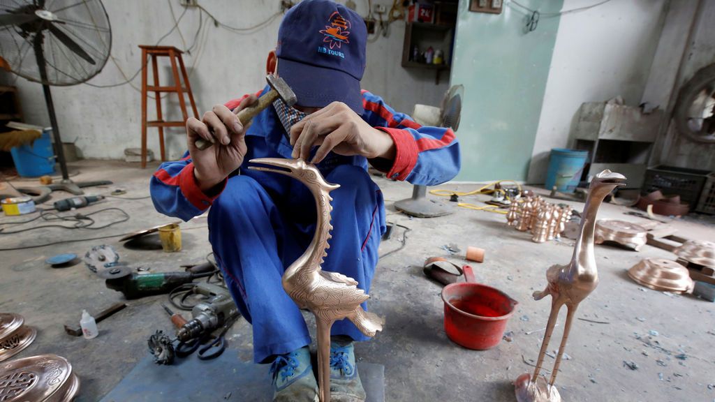 Un hombre talla figuras de bronce en Vietnam