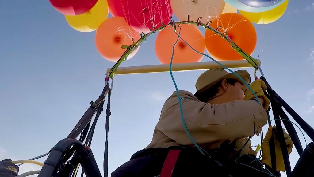 Un hombre sentado en una silla de camping sobrevuela Johanesburgo impulsado por globos