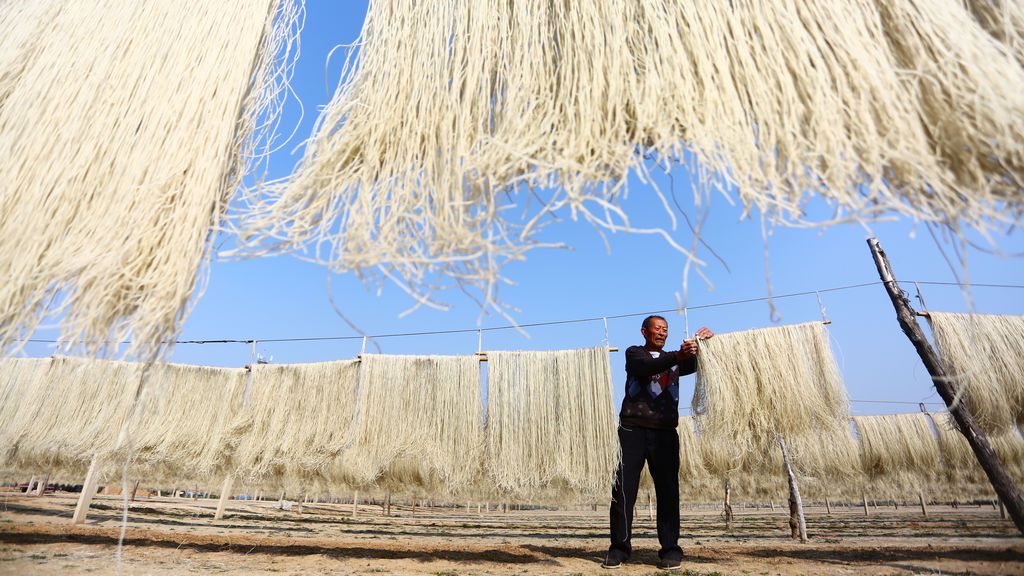 Un hombre cuelga hebras de fideos de batata para secar en Zaozhuang, provincia de Shandong, China, el 2 de noviembre de 2017