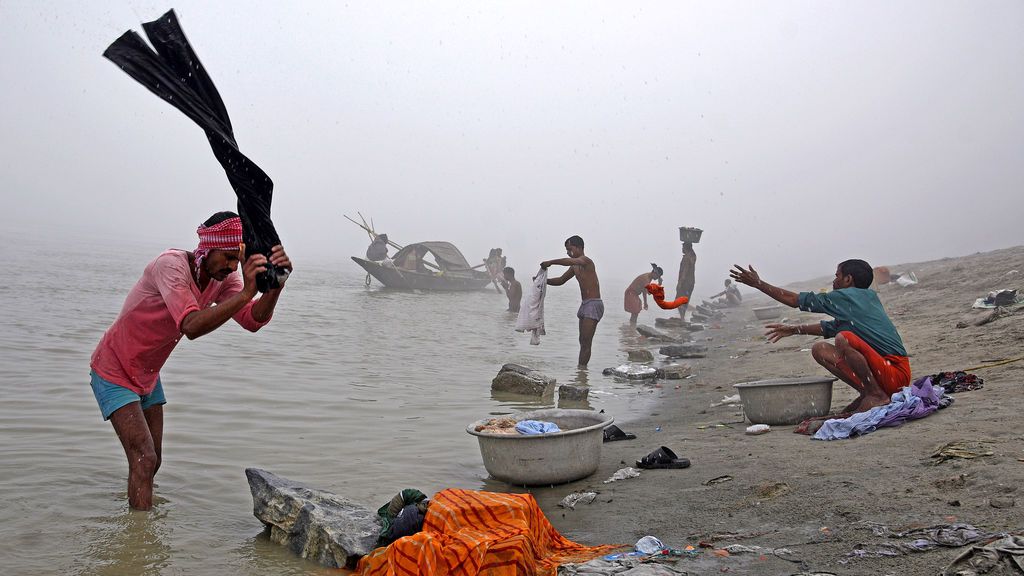 La gente lava ropa en las orillas del río Brahmaputra en una mañana de niebla de invierno en Guwahati, India