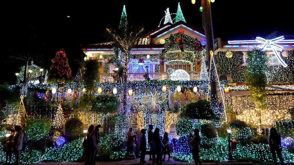 La gente se hace fotos con una casa llena de luces con motivos navideños en Rizal, Manila