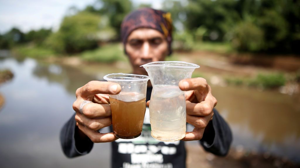 Un activista ambiental sostiene un vaso de agua del río Citarum y otro de un afluente que atraviesa un área densamente poblada con fábricas textiles al sureste de Bandung, provincia de Java Occidental, Indonesia