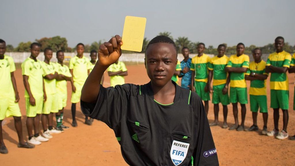 El joven de 14 años que arbitra en Liberia con la tarjeta amarilla que recibió De Jong en la final del Mundial 2010