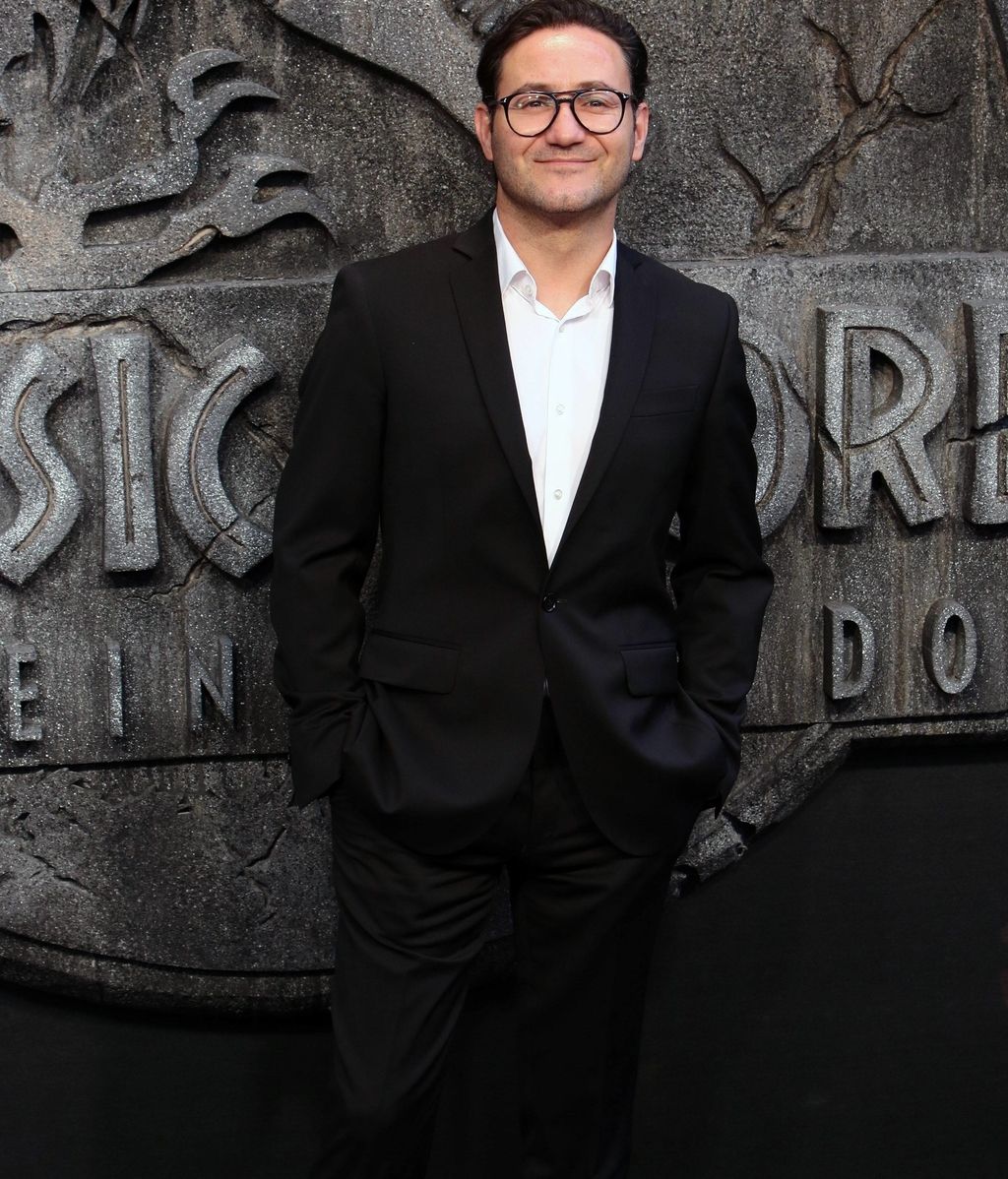 El actor Carlos Santos, con traje negro y camisa blanca