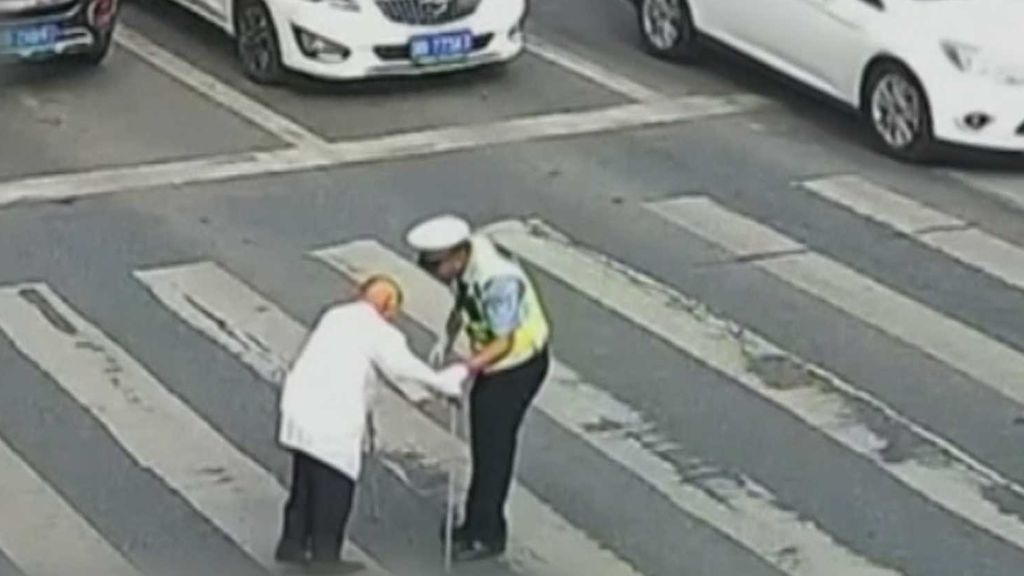 Un policía ayuda a cruzar la calle a un anciano de una inusual manera