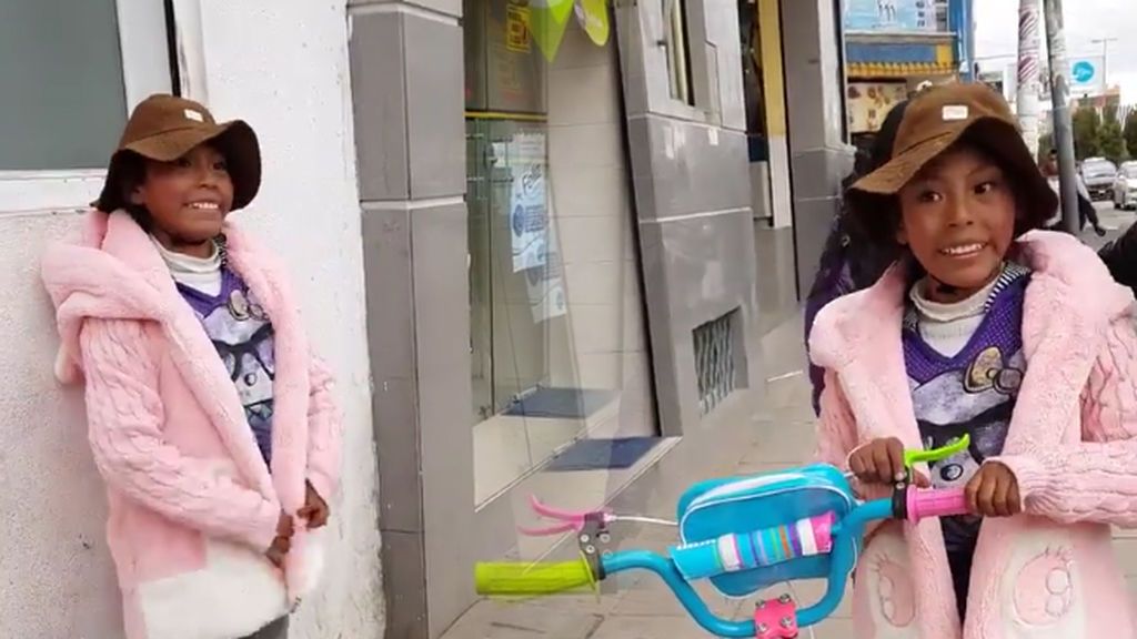 La sonrisa de una niña boliviana que vende fruta en la calle cuando otra se le acerca para regalarle su bici