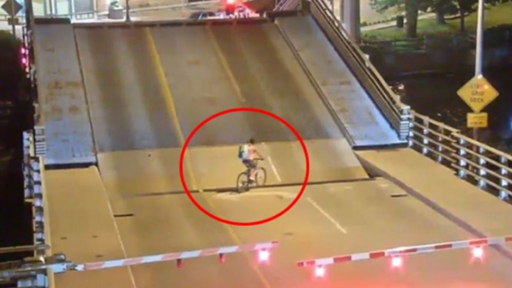 Una ciclista intenta pasar justo cuando se levanta el puente levadizo