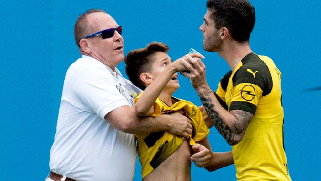 Pulisic, jugador del Dortmund, se enfrenta a la seguridad para defender a un niño que saltó al césped para hacerse una foto con él