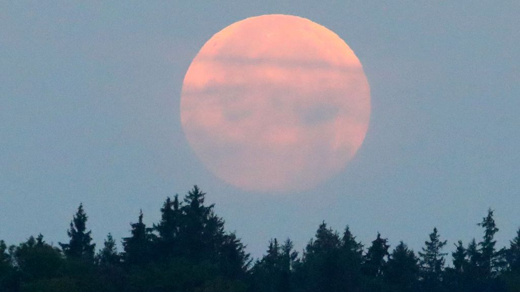 Medio mundo pendiente del eclipse de luna, difuminado por las nubes