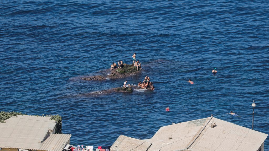 Hombres descansando en una roca en el mar en Argelia