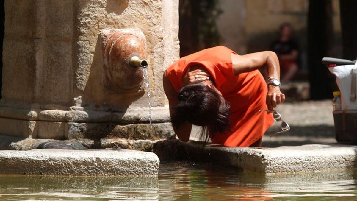 Una mujer se refresca en una fuente en Córdoba