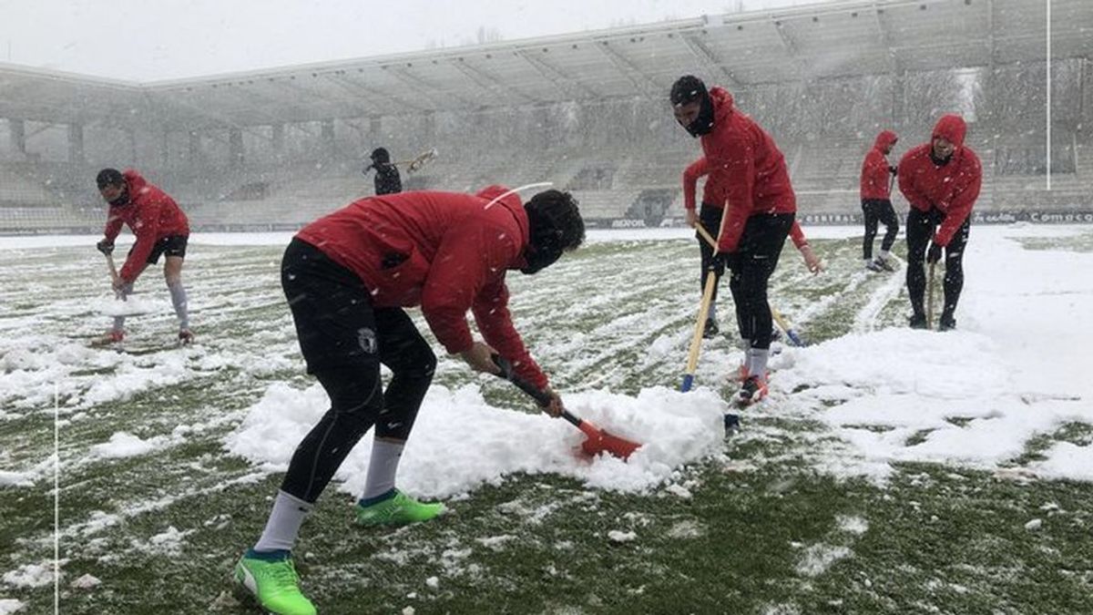 Los jugadores del Burgos C.F. calientan recogiendo la nieve que ha invadido su estadio Los jugadores del Burgos C.F. calientan recogiendo la nieve que ha invadido su estadio