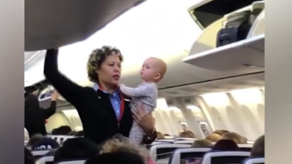 Una azafata ayuda a tranquilizar a un bebé mientras prepara el avión para el despegue