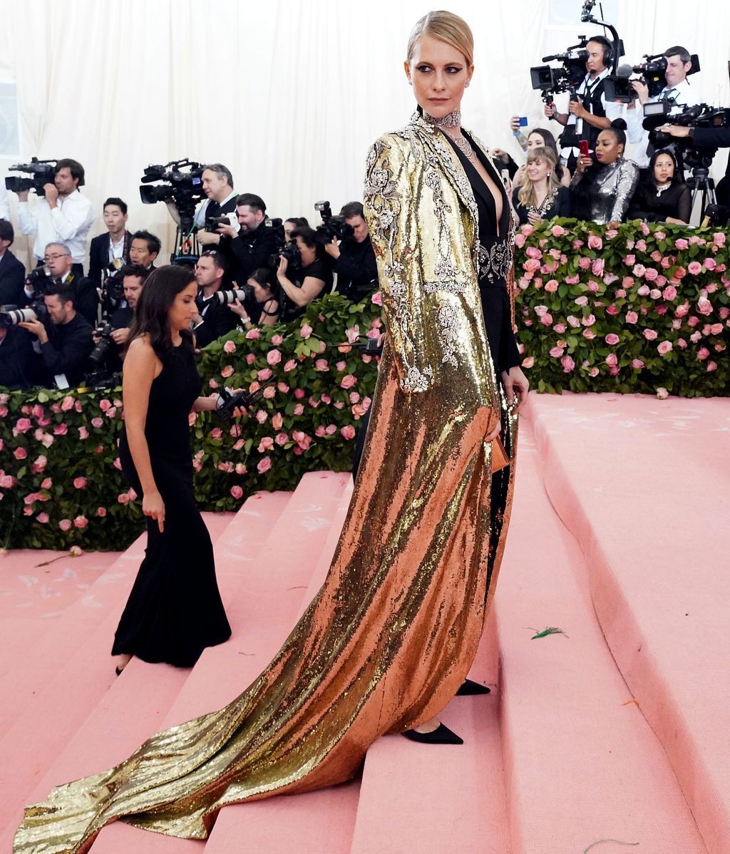 Poppy Delevingne con vestido negro y abrigo de lentejuelas dorado y plateado