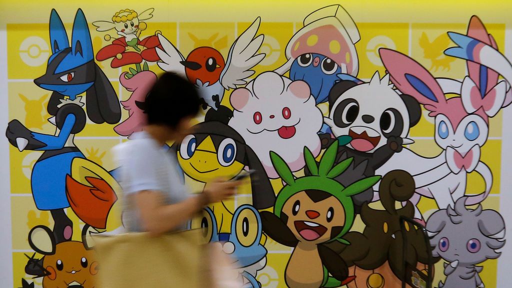 Una mujer camina frente a una imagen de personajes de Pokémon