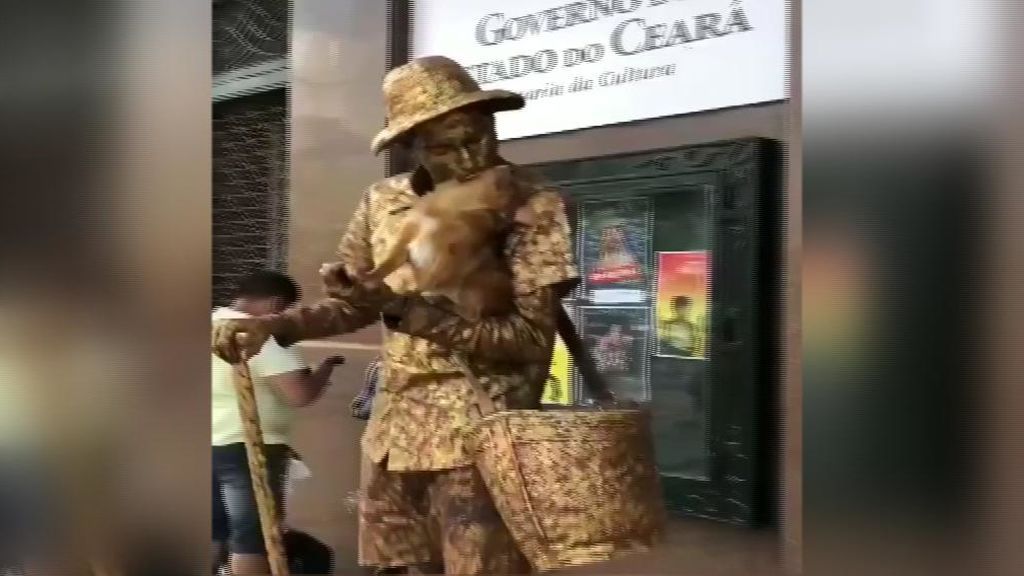 Un perro posa como una estatua junto a su dueño en un centro comercial de Brasil