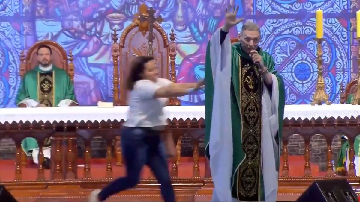 Una mujer empuja y tira del escenario a un cura mientras oficiaba una misa
