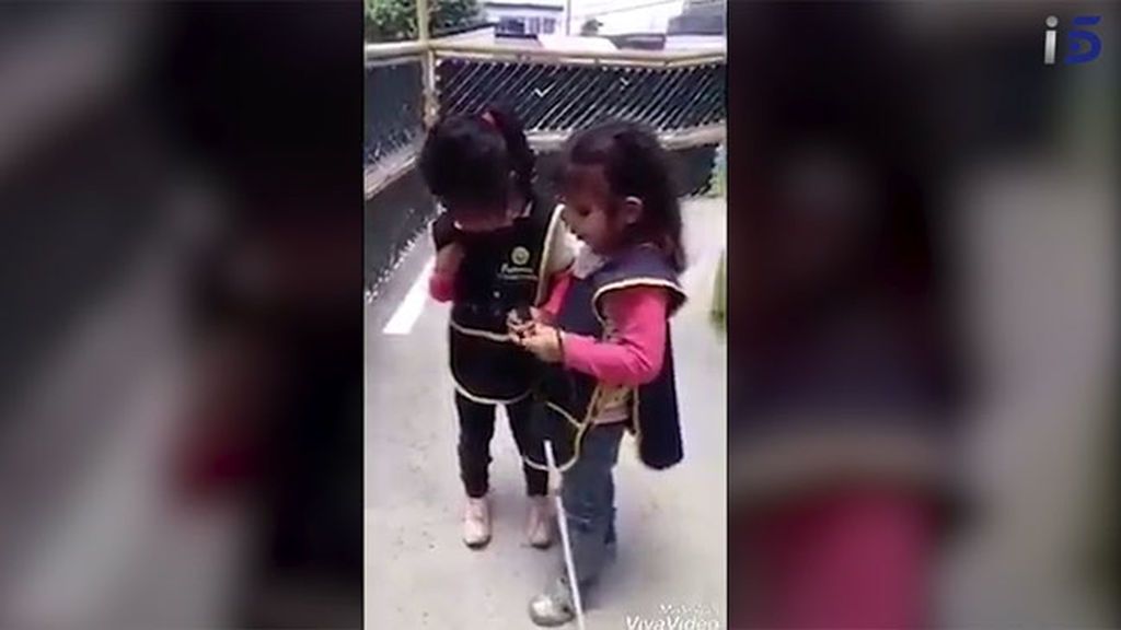 Una niña invidente ayuda a su amiga a usar el bastón guía