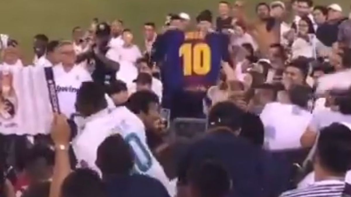 Un aficionado del Barça recibe una lluvia de objetos tras mostrar una camiseta de Messi en el derbi entre Real Madrid y Atlético