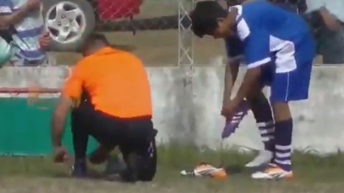 Un árbitro le da sus botas a un jugador para que pueda seguir jugando después de que se le rompieran
