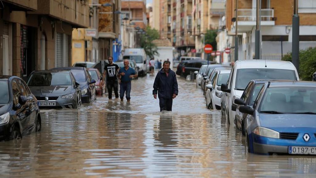 Vecinos caminando por Orihuela con el agua a la altura de la rodilla