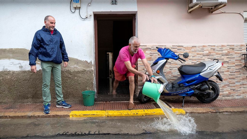 Un hombre achica el agua que ha inundado su vivienda del barrio de las casas baratas de Blanca, Murcia,