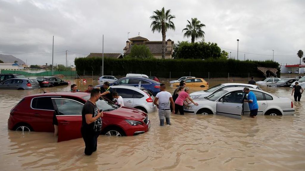 Vecinos cerca de los coches inundados en Orihuela