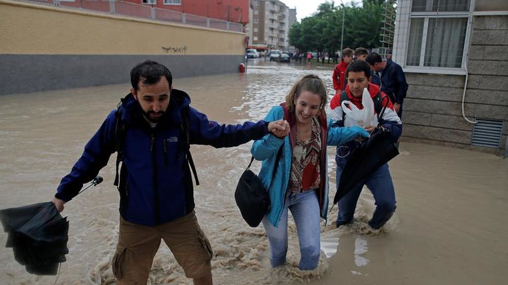 La gente camina por una calle inundada cerca del desbordante río Segura