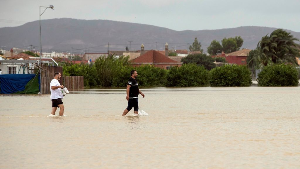 Dos vecinos de la pedanía de El Siscar, en Santomera, caminan por una zona inundada