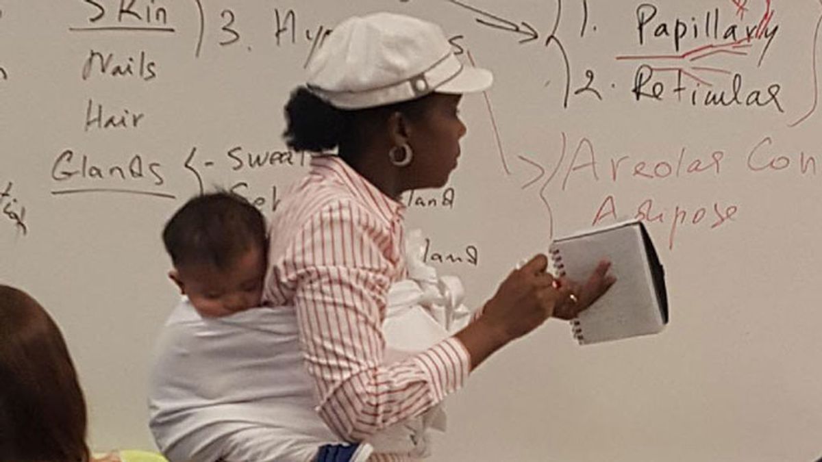 Una profesora se cuelga a la espalda al bebé de una alumna para que pueda tomar apuntes